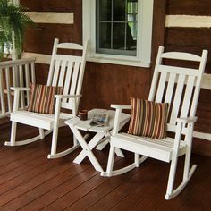 two white rocking chairs sitting on top of a wooden porch