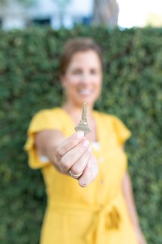 a woman in a yellow dress holding up a key to the camera with a smile on her face