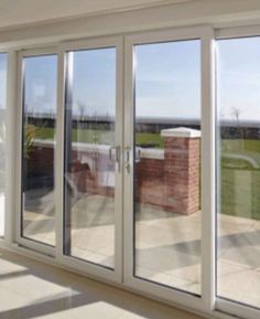 an empty room with sliding glass doors leading to a balcony overlooking the grass and sky