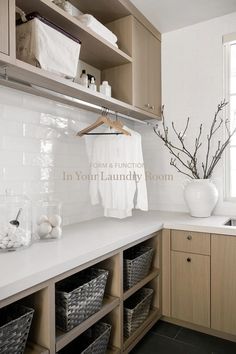 a white kitchen with wooden cabinets and shelves filled with dishes, towels and other items