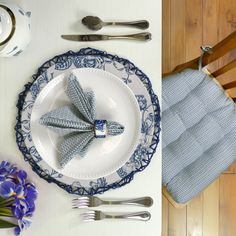 the table is set with blue and white plates, silverware, and napkins