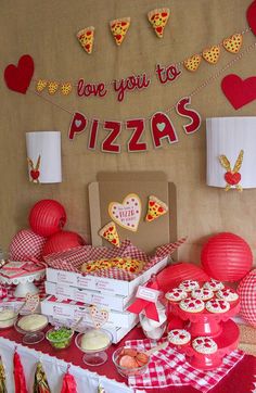 a table topped with pizzas and cupcakes covered in toppings next to paper lanterns