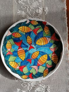 a bowl with fish painted on it sitting on a doily