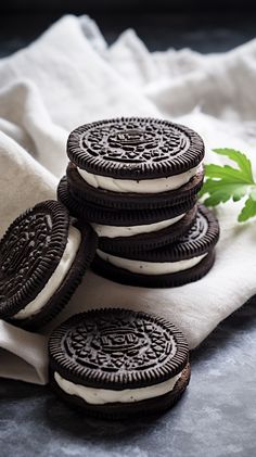 oreo cookies with white cream filling on a napkin next to a sprig of green leaves