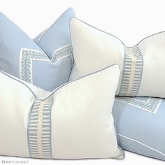 three blue and white pillows stacked on top of each other, one with an embroidered design