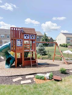 a wooden play set in the middle of a yard with a slide and climbing frame