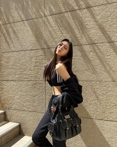 a woman standing next to a wall holding a purse