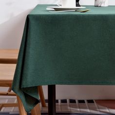 a table with a green cloth on it and two white vases next to it