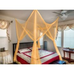 a canopy bed in a bedroom next to a window