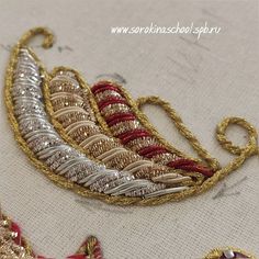 some very pretty gold and red brooches on a white table cloth with beads