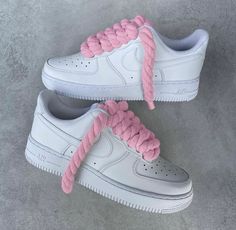 two white sneakers with pink laces on them