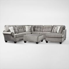 a large sectional couch with pillows on the back and footstools in grey fabric