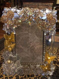 an ornate photo frame is adorned with gold and silver flowers, butterflies, and pearls