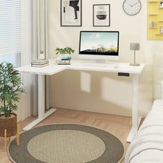 a white desk with a computer on top of it in front of a wall mounted clock