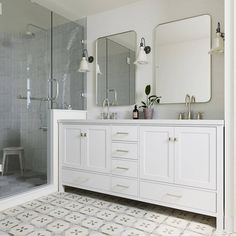 a bathroom with white cabinets and marble counter tops, two mirrors on the wall above the sink