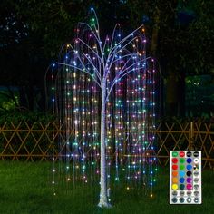 a lighted tree in the middle of a yard at night with colored lights on it