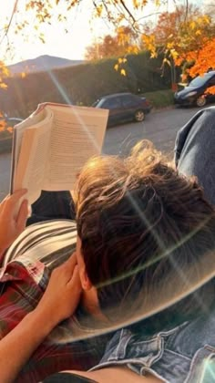 a person laying down reading a book in the sun with their head on his hands