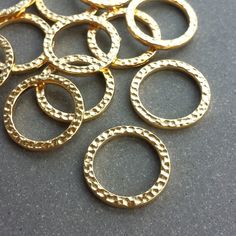 This listing is for 4 or 10 pcs of these Gold 19mm Hammered Rings by Tierra Cast. These lovely rings feature a hammered texture on the front and back and a shiny gold-plated finish. They are solid, sturdy, closed rings. These high-quality components are made of electroplated pewter here in the US and are 100% lead-free. Each ring measures approximately 19mm wide x 2mm thick with an 14.3mm inner diameter. These pieces are extremely lightweight, weighing approximately 1.4 grams each. Please choose Metal Rings For Jewelry Making, 14k Gold Hammered Rings, Rustic Hammered Brass Jewelry, Hammered Gold-tone Brass Jewelry, Adjustable Hammered Brass Ring, Hammered Brass Spiral Jewelry, Pewter Ring, Hammered Gold Ring, Hammered Rings