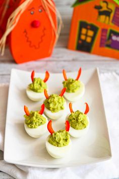 deviled eggs with guacamole and carrots on a white plate