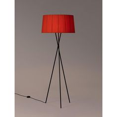 a floor lamp with a red shade on the base and a black metal tripod