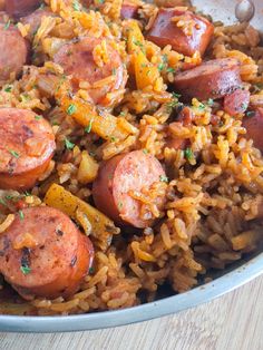 a bowl filled with rice and sausage on top of a wooden table