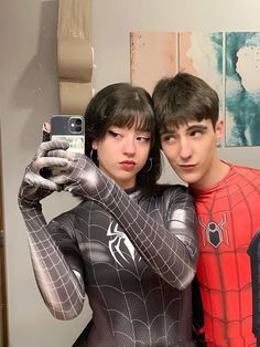 two people dressed up as spider - man and woman taking a selfie in front of a mirror