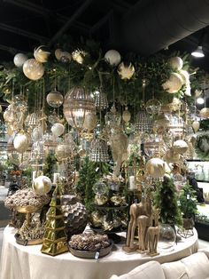 a table topped with lots of christmas ornaments and baubles hanging from the ceiling