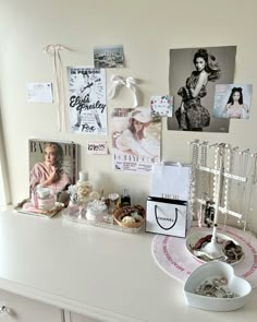 a white dresser topped with pictures and jewelry