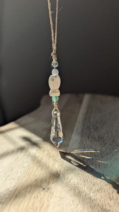 a glass bead hanging from a string on a wooden table