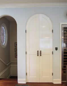 an arched doorway leads to a wine cellar in the corner of this home's entryway