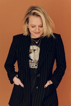 a woman with blonde hair wearing a black and white pinstripe blazer jacket