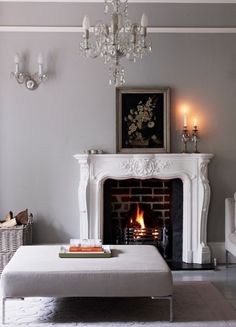 a living room filled with furniture and a fire place next to a white couch under a chandelier