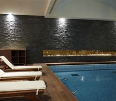 an indoor swimming pool with chaise lounges next to it and a fire place