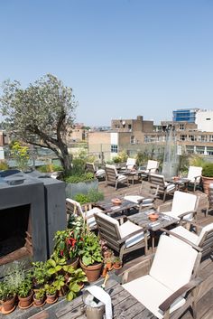 an outdoor patio with chairs, tables and potted plants on the roof top deck