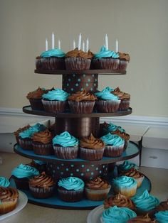 three tiered cupcake display with blue frosting and chocolate cupcakes on plates