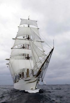 a large white sail boat in the middle of the ocean