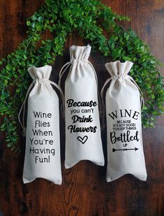 three wine bags sitting on top of a wooden table next to green plants and leaves