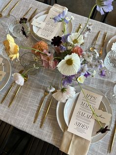 the table is set with flowers and place cards