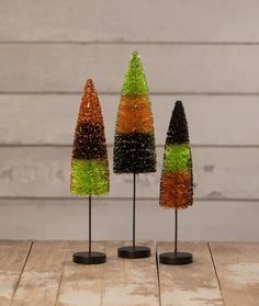 three small trees made out of yarn on top of a wooden table next to each other