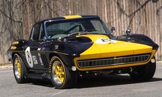 a black and yellow race car parked in front of a wooden fence