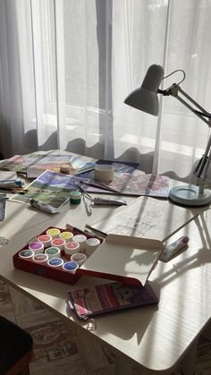 the desk is covered with art supplies, such as watercolors and pencils