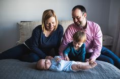 a man, woman and baby sitting on a bed