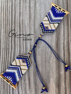 the blue and white beaded bracelet is hanging on a wooden surface with gold accents