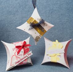 three folded origami ornaments with bows and tags on them, one is happy valentine's day