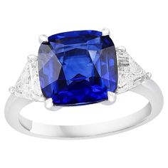 Showcases a Cushion cut, Vibrant color Blue Sapphire weighing 4.09 carats, flanked by two pointed trillion cut diamonds weighing 0.96 carats total. Elegantly set in a polished platinum composition. American Modern, Engagement Rings Platinum, Blue Sapphire Diamond, Three Stone Engagement, Three Stone Engagement Rings, Three Stone Rings, Three Stone, Jewelry Gift Box, Cushion Cut