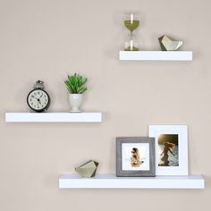 three white shelves with pictures and two framed photos on them, one has a clock