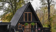 a - frame house with black siding and wood trimmings on the front porch