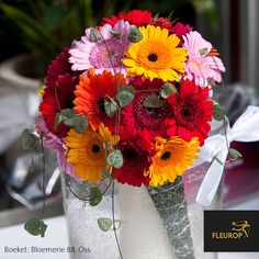 a vase filled with lots of different colored flowers