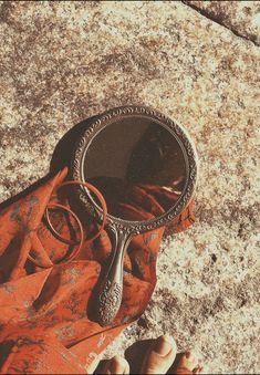 a person's hand holding a mirror on the ground