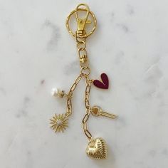 a gold keychain with charms attached to it on a white marble countertop